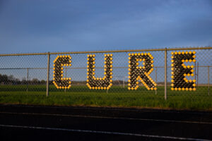 A chainlink fence with letters to spell "CURE".